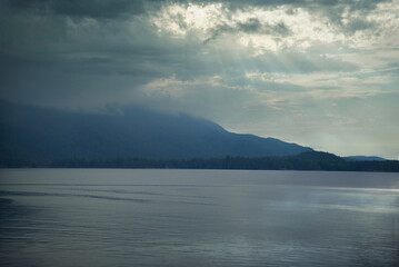 rain cloud coming down the mountain next to the ocean