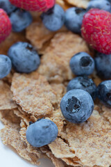 Whole wheat granola breakfast with organic blueberries and raspberries. Close up