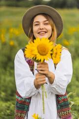 A girl in a field with sunflowers rejoices and enjoys life. A walk in a sunflower field. Agriculture. Rural life on the farm. The girl holds sunflower flowers in her hands.