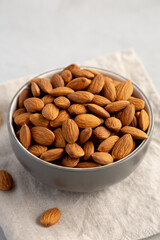 Raw Organic Almonds in a Bowl on a gray background, side view.