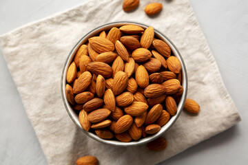 Raw Organic Almonds in a Bowl on a gray background, top view.