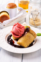 Traditional French rhum baba with cherry ice cream and amarena sauce served as close-up on a classic design plate