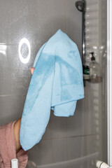 A woman wipes the glass surface of the shower cabin with a rag