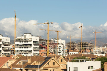 construction cranes between new buildings and others under construction; real estate speculation...