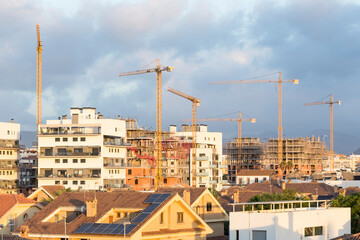 view of various cranes in a city, rooftops and buildings under construction. Speculation, industry.