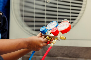 Close up of trained engineer holding manifold gauges used for checking air conditioner refrigerant....