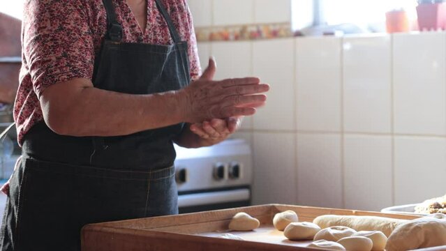 Candid scene of Unidentified Latina Woman Crafting Dough with Hands in Rustic Home Kitchen