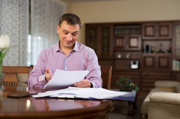 Positive man reads documents while sitting at the table. High quality photo