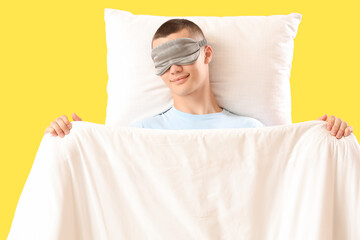 Young man sleeping on yellow background, top view