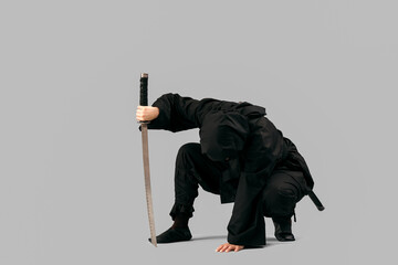 Female ninja with sword on grey background © Pixel-Shot