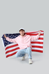 Young man with USA flag on light background