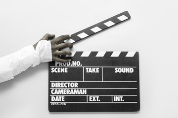 Hand of zombie with clapperboard on white background. Halloween celebration