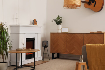 Interior of modern living room with stylish fireplace and chest of drawers