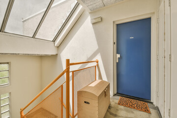 a blue door in a white room with an orange handrail on the floor and stairs leading up to it