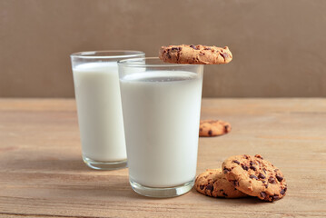 Glasses of milk and tasty cookies with chocolate chips on table