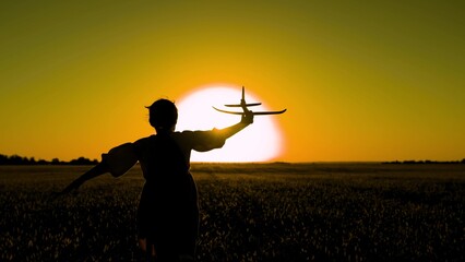 Happy child girl runs with toy airplane on field in sunset. Girl wants to become pilot, astronaut. Slow motion. Children play toy airplane. Teenager dreams of flying becoming pilot. Child aviator, sun
