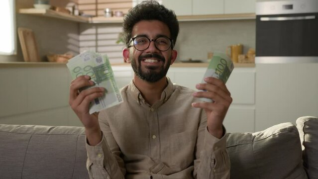 Happy rich man Arabian Indian wealthy businessman counting money cash salary finance business investment financial wage winning prize domestic finances count stack of euro banknotes at home kitchen