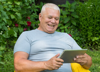 elderly man in the garden with laptop tablet