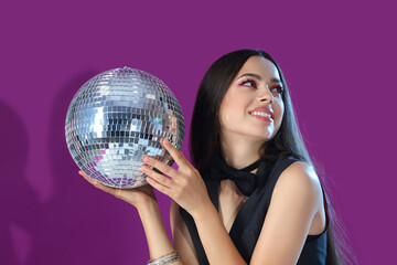 Stylish young woman with disco ball on purple background