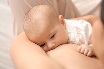 Young woman breastfeeding her baby in bedroom, closeup