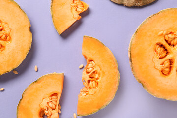 Pieces of sweet melon and seeds on lilac background