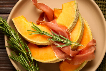 Plate with tasty melon, prosciutto and rosemary, closeup