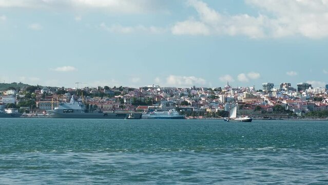 View of Tagus river with tourist boat and moored NATO warships in Lisbon, Portugal