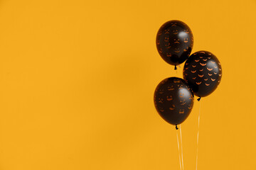 Different black Halloween balloons on orange background