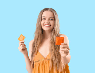 Young woman with condoms on blue background