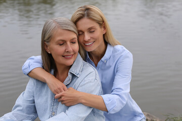 Obraz premium Happy mature mother and her daughter hugging near pond