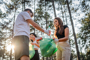 teenage friends young men women pick up waste garbage to clean forest