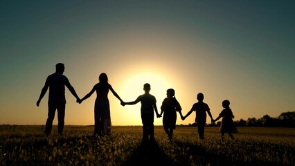 Parents, happy children go to sun. People walk in nature. Big family holding hands walk in park at sunset. Dad mom, son, daughter walk, walk together outdoors. Concept of happy family childhood dream