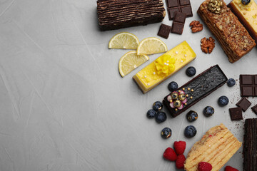 Flat lay composition with different tasty cakes on light grey table. Space for text