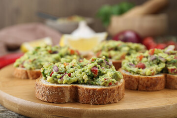 Slices of bread with tasty guacamole on wooden table, closeup