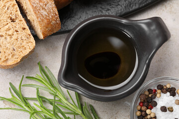 Saucepan of organic balsamic vinegar with oil, spices and bread slices on beige table, flat lay