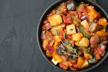 Dish with tasty ratatouille on black table, top view. Space for text