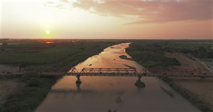 Aerial shot of Tumbes river, bridge and city at sunset. Tropical city at north of Per&uacute;. 