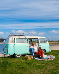 couple doing a road trip with an old vintage car in the Dutch flower bulb region with tulip fields...