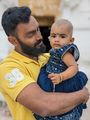 A happy, smiling uncle spends time with his niece, playing and holding the baby on his shoulder,...