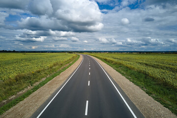 Aerial view of empty intercity road between green agricultural fields. Top view from drone of highway roadway