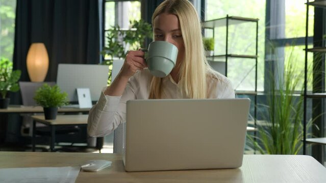Caucasian businesswoman business manager use laptop check email overwork computer at desk relaxed girl stretch hands woman have coffee break in office relax for tea drink hot beverage free time pause