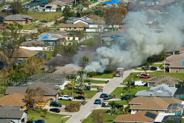 Aerial view of house on fire and firefighters extinguishing flames after short circuit caused spark...