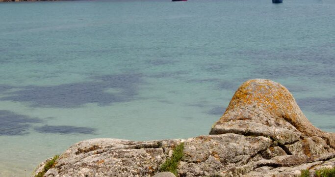 Turquoise sea with eroded rock in foreground on St Agnes and Gugh at the Isles of Scilly
