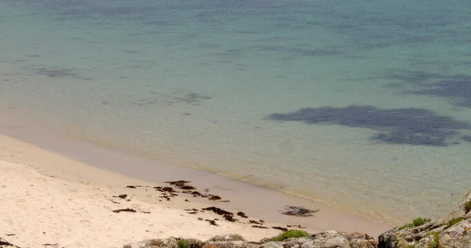 looking down onto the beach with the sea lapping on to the sand on St Agnes and Gugh at the Isles of Scilly
