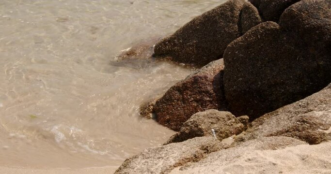 a series of eroded rocks and the sea lapping around then on the beach on St Agnes at the Isles of Scilly 2 of 6