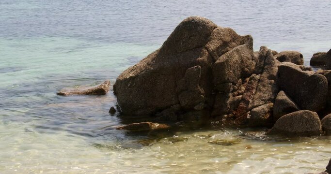 a series of eroded rocks and the sea lapping around then on the beach on St Agnes at the Isles of Scilly 1 of 6