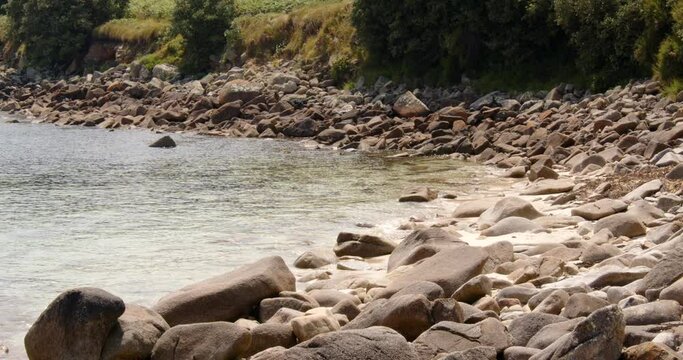 Wide shot waves lapping on the rocky shore at St Agnes at the Isles of Scilly
