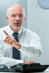 Senior man, desk, firmly disapproves practices