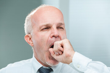 Elderly clerk yawns, hand, fatigue hinted