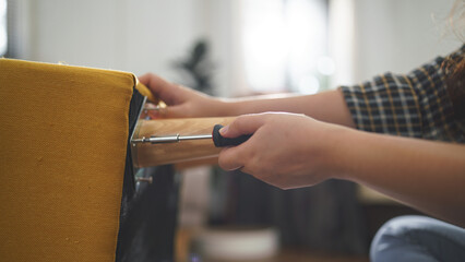 Women tighten screw with screwdriver equipment for assembling leg of chair and making furniture